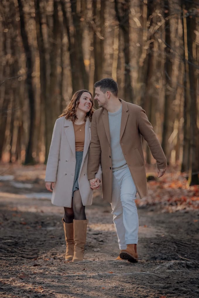 Paar in Wollmänteln in Beige und Camel beim Spaziergang durch den Herbstwald