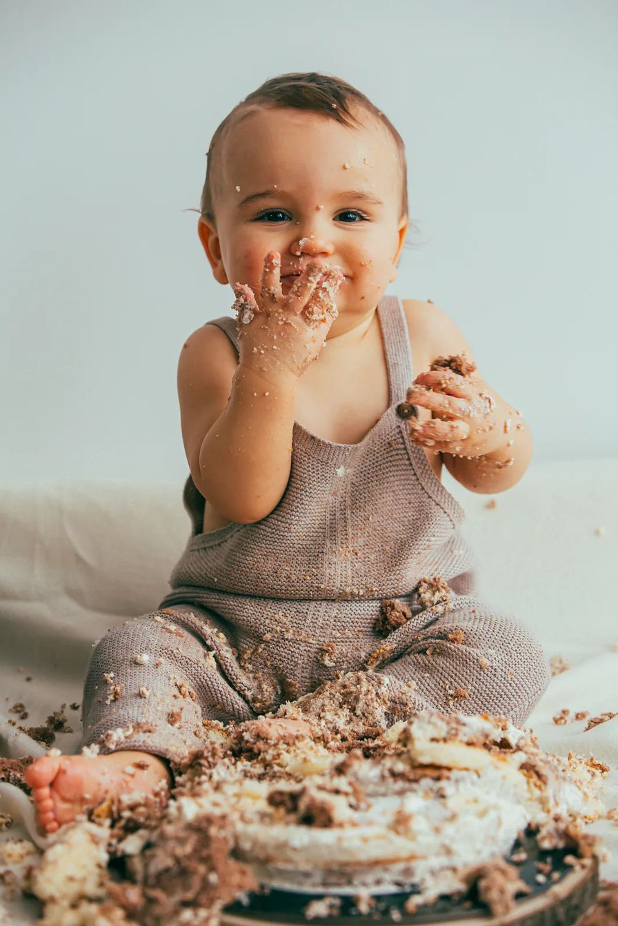 Baby in Strick-Latzhose beim Cake Smash